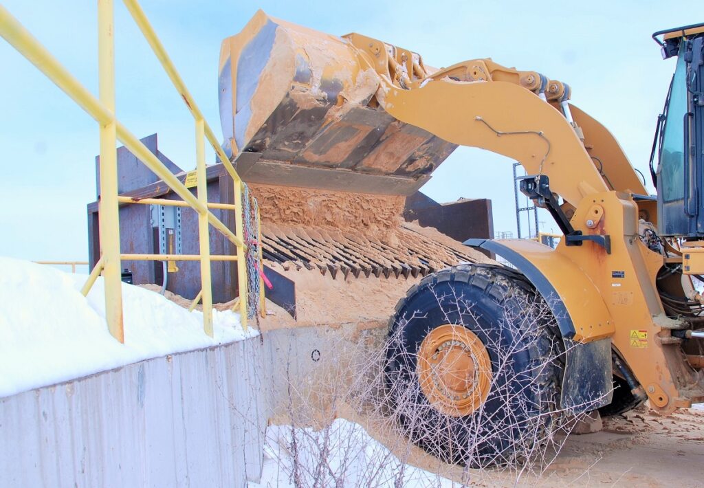 Frontend loader loading sand into a bin with newly installed heated grizzlies.